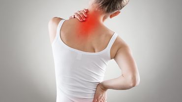 Frau von hinten mit roten Schmerzpunkten an Lendenwirbelsäule und Nacken