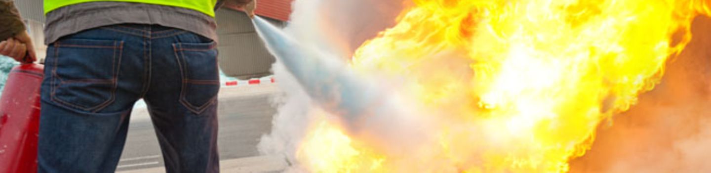Ein Brandschutzhelfer löscht mit einem Feuerlöscher einen Brand